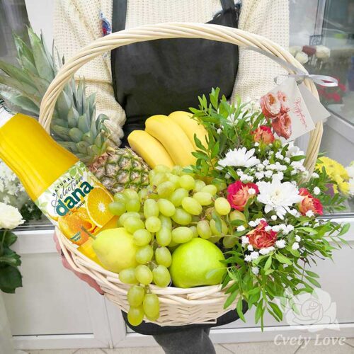 Фрукты, цветы и напиток в белой корзине